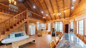 Une cabine spacieuse avec un intérieur en bois, un coin repas avec une table en marbre, une cuisine et un escalier menant à une mezzanine.