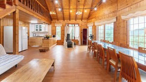 Une cabane en bois spacieuse, dotée d’un grand espace repas, d’une cuisine et d’un salon confortable.
