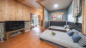 Una habitación acogedora con televisión, dos camas, chimenea de piedra y un ventanal grande.