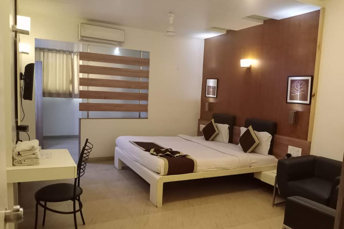 A hotel room with a bed, a desk, a chair, and a wardrobe.