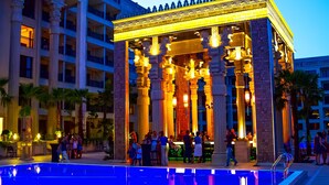 A hotel lobby with a pool, columns, and a bar area.