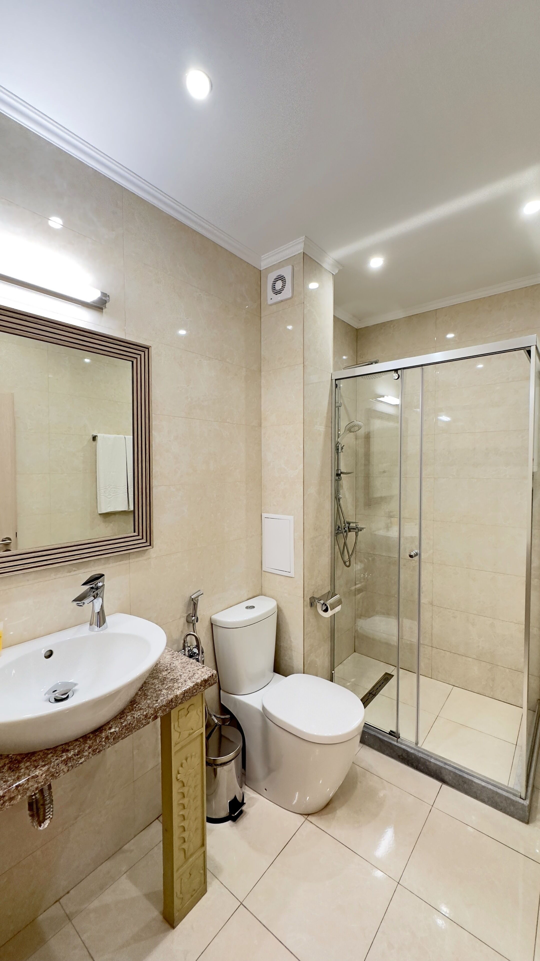 A modern bathroom with a sink, toilet, and glass-enclosed shower.