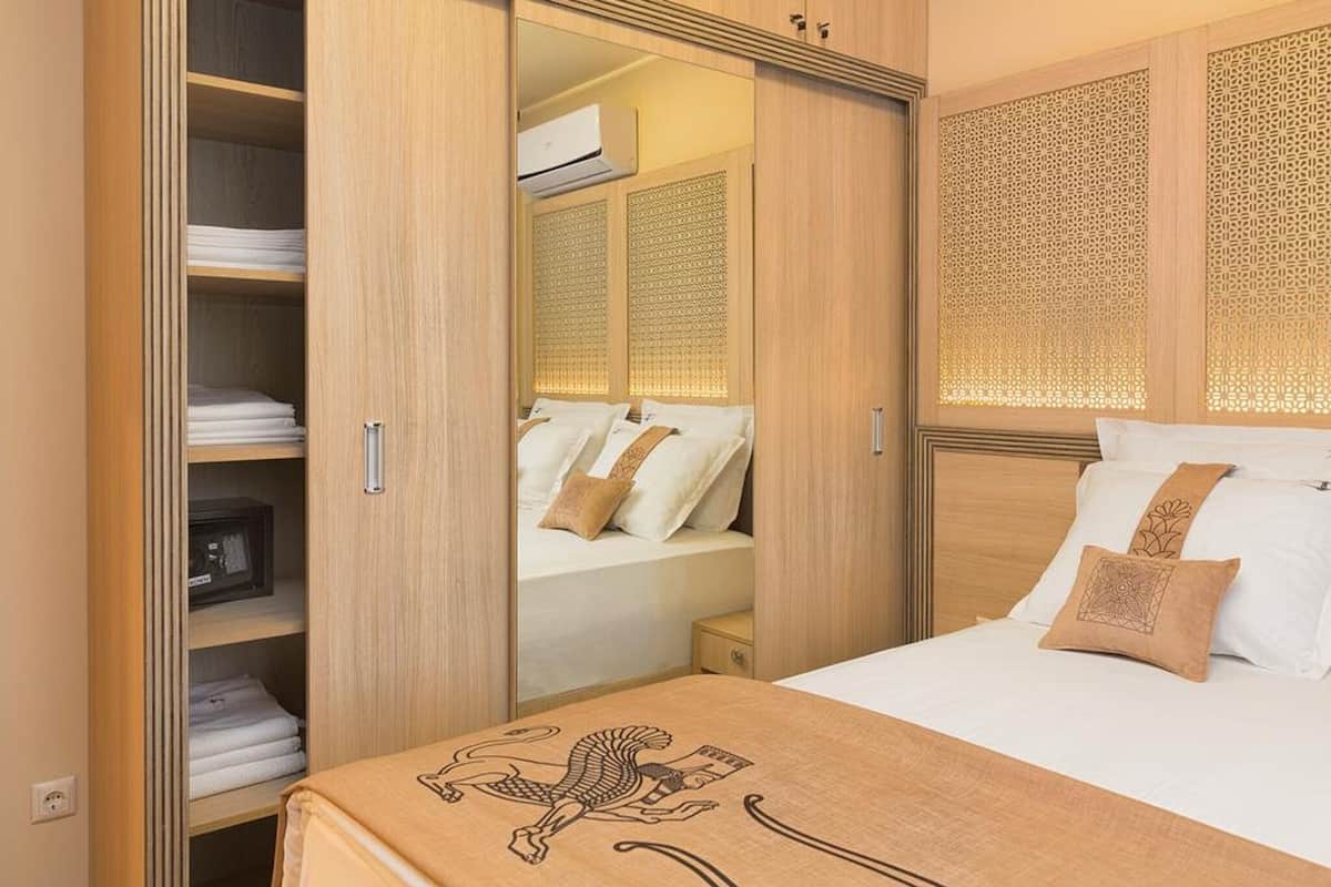 A bedroom with a bed, a wardrobe, and a mirror.