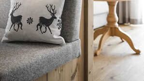 A grey upholstered chair with a decorative pillow featuring reindeer designs. - MAGNIFICENT CHALET COMFORT AND MODERNITY: OUR APARTMENTS IN PUSTERTAL (St. Lorenzen)