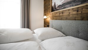 A hotel room with a wooden headboard, a framed landscape painting, and a bedside lamp. - MAGNIFICENT CHALET COMFORT AND MODERNITY: OUR APARTMENTS IN PUSTERTAL (St. Lorenzen)