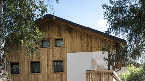 A modern building with a wooden facade and white walls, featuring multiple windows and a balcony. - MAGNIFICENT CHALET COMFORT AND MODERNITY: OUR APARTMENTS IN PUSTERTAL (St. Lorenzen)