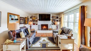 Una sala de estar con chimenea, sofás de cuero, una mesa de centro y un televisor de pared.