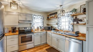 Una cocina moderna con electrodomésticos de acero inoxidable, encimeras de madera y armarios de colores claros.
