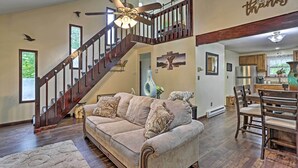 A spacious living room with a wooden staircase, a dining area with wooden chairs, and a kitchen in the background. - 15 Mi to Camelback Ski Resort: Home w/ Deck! (Tobyhanna)
