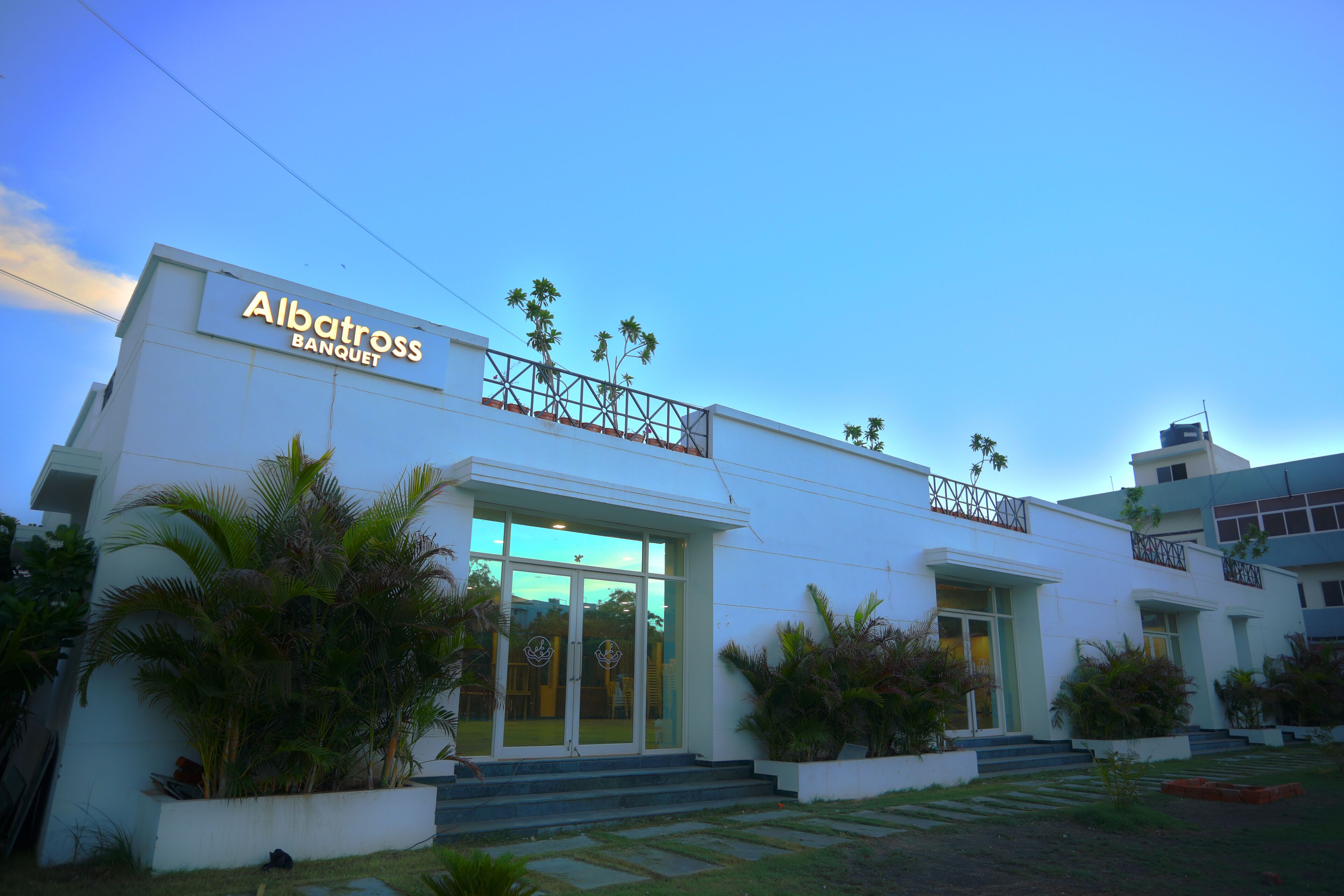 A modern building with a sign reading "Albatross Banquet." It features a white facade, large glass windows, and a balcony with railing.