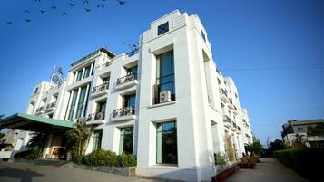 Stylish building with balconies and large windows, set amidst landscaped gardens and a paved walkway.