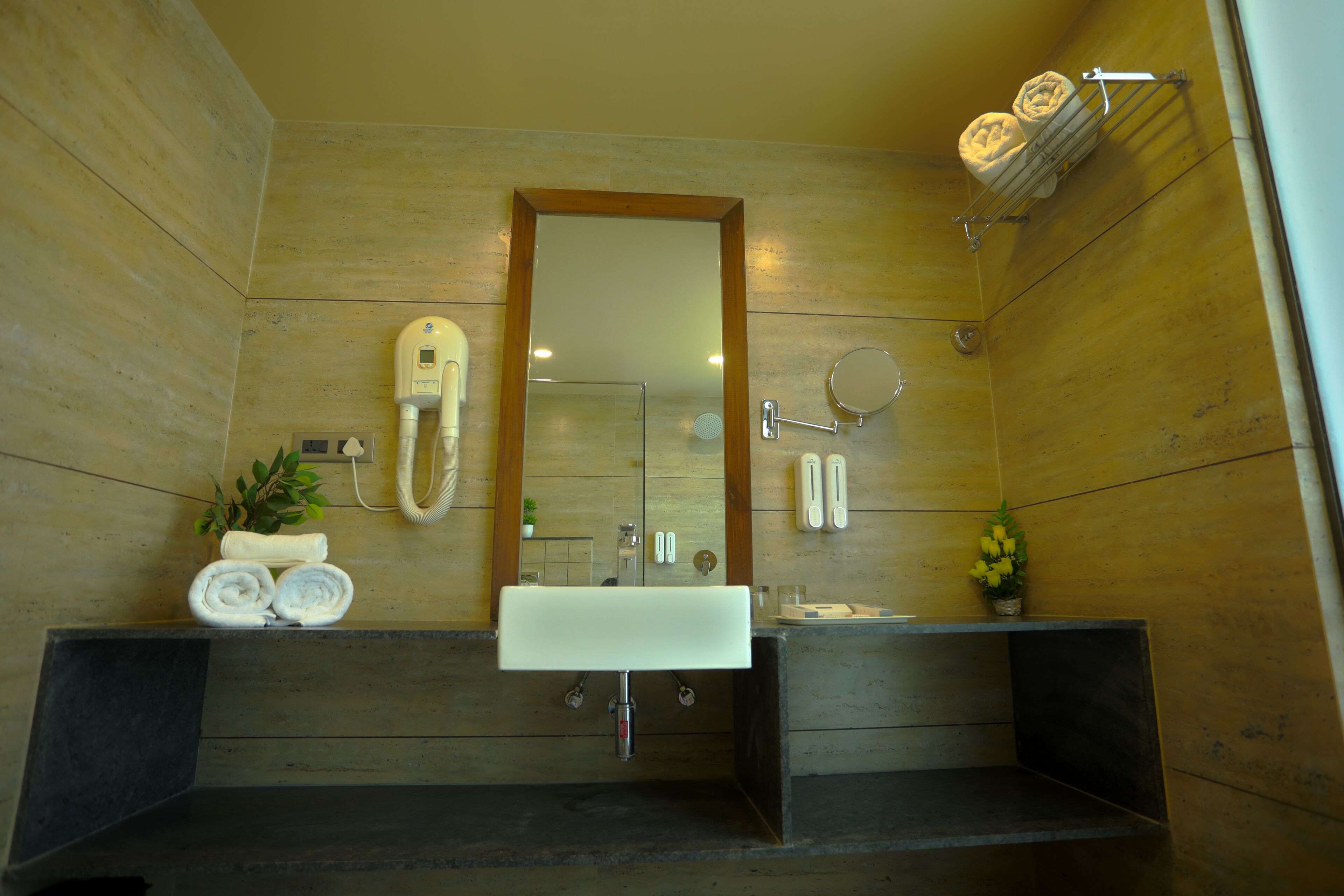 Un baño moderno con pared de madera, un espejo grande, un lavabo blanco y un perchero para toallas.