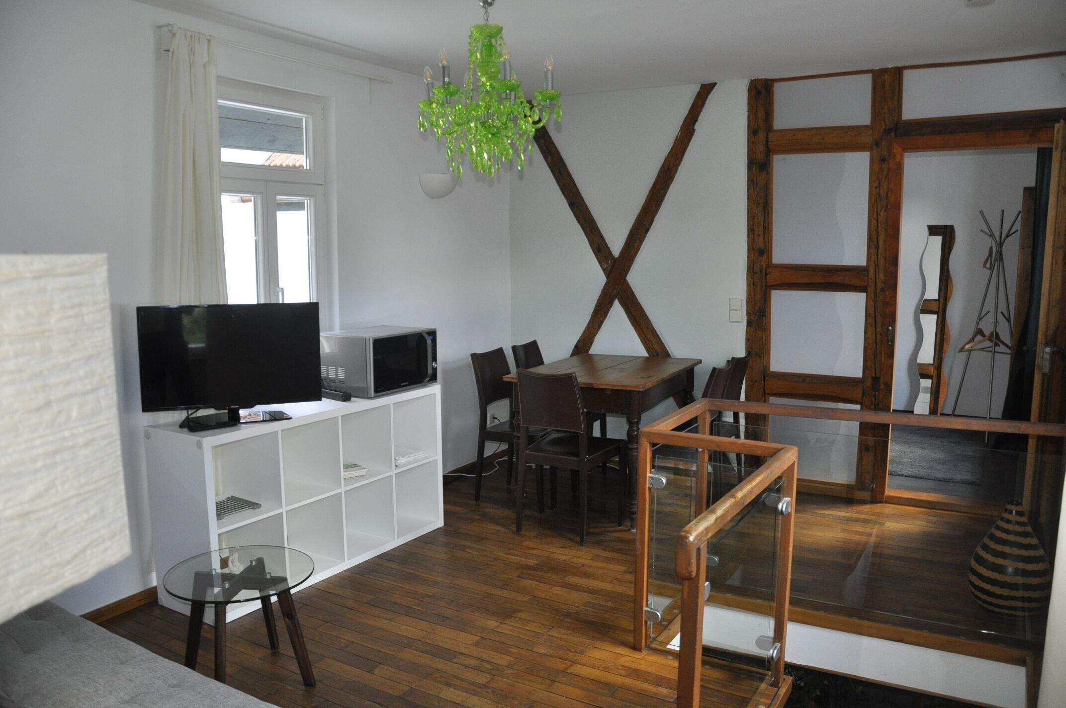 Ett modernt vardagsrum med en platt-TV, ett matbord i trä och ett soffbord i glas.