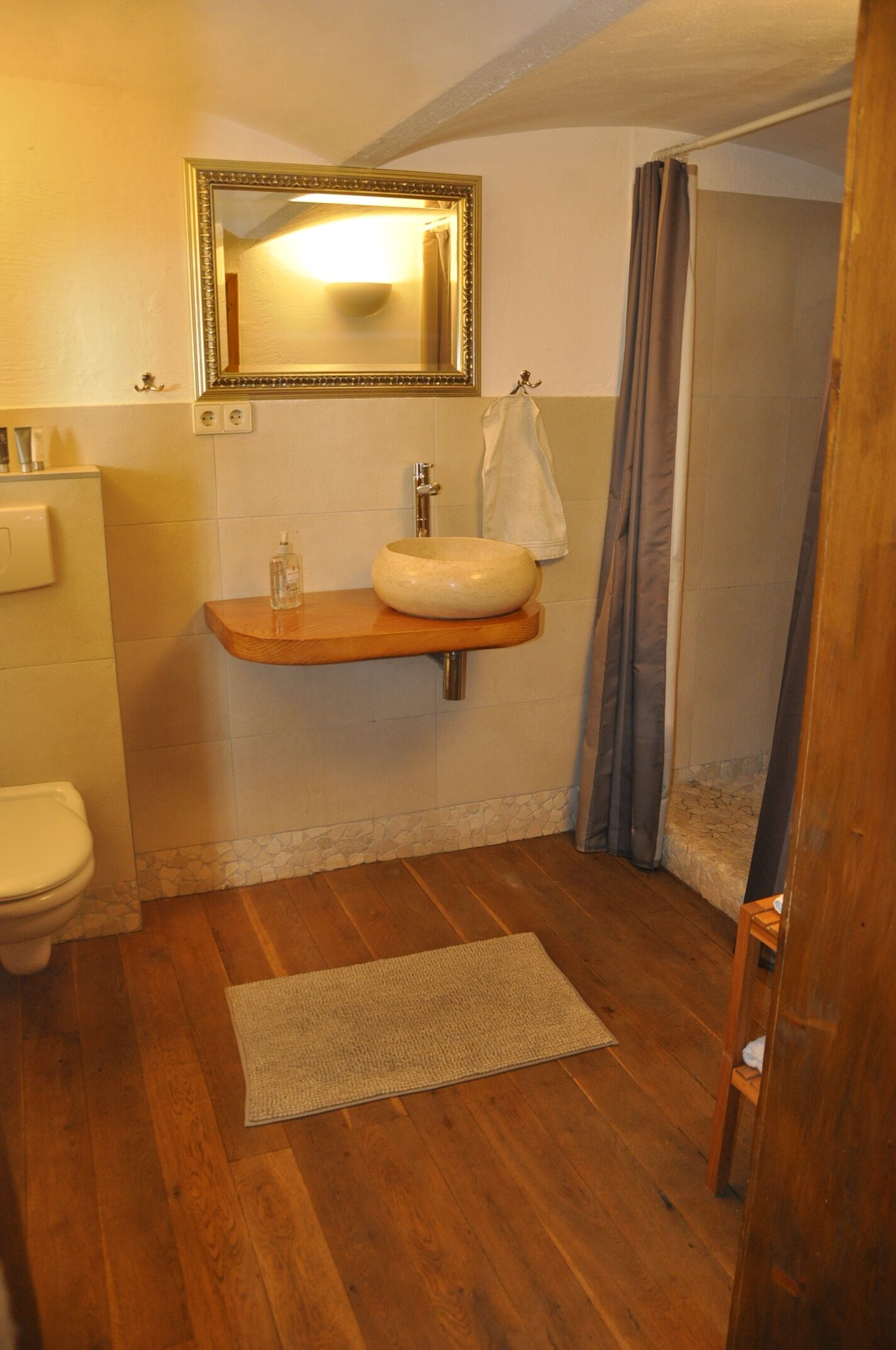 Un baño con tocador de madera, un espejo grande, un inodoro y una cortina de ducha.