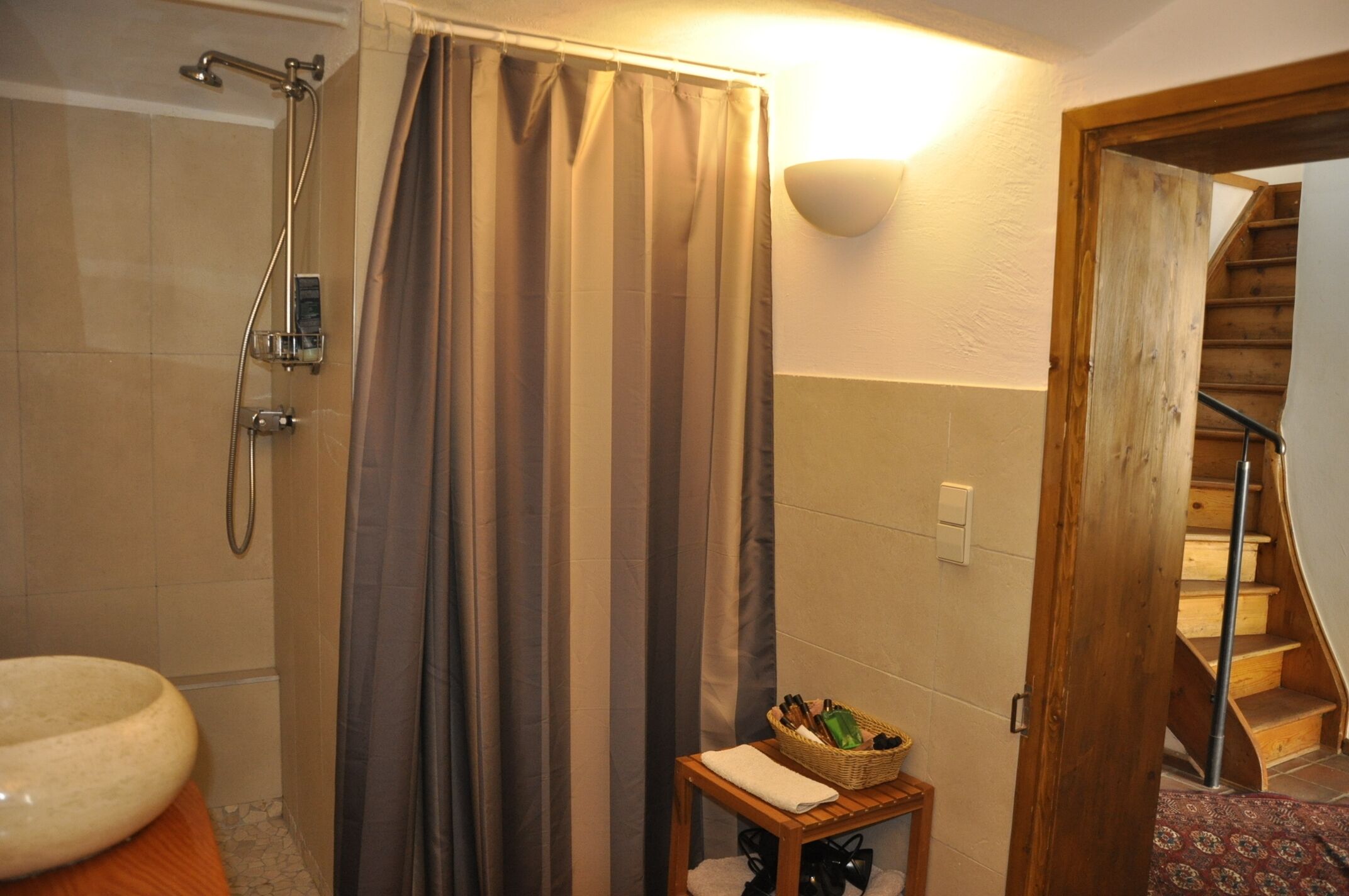 Ein Badezimmer mit Dusche, Toilette und einem kleinen Tisch mit einem Korb.