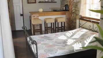A compact room with a bed, a small kitchenette, and a dining area.