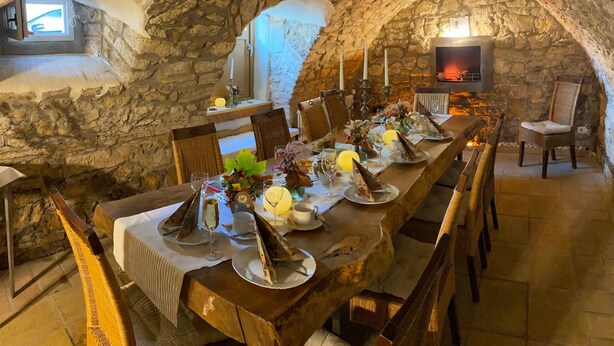 A stone-walled dining area with a long table set for a meal, featuring candles, plates, and glasses. - Geibelhof (Karben)