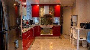 Une cuisine moderne avec des meubles de couleur rouge, des appareils en acier inoxydable et un plan de travail en granit.