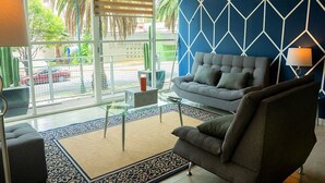 Un salon moderne avec un canapé gris, une table basse en verre et un tapis à motifs.