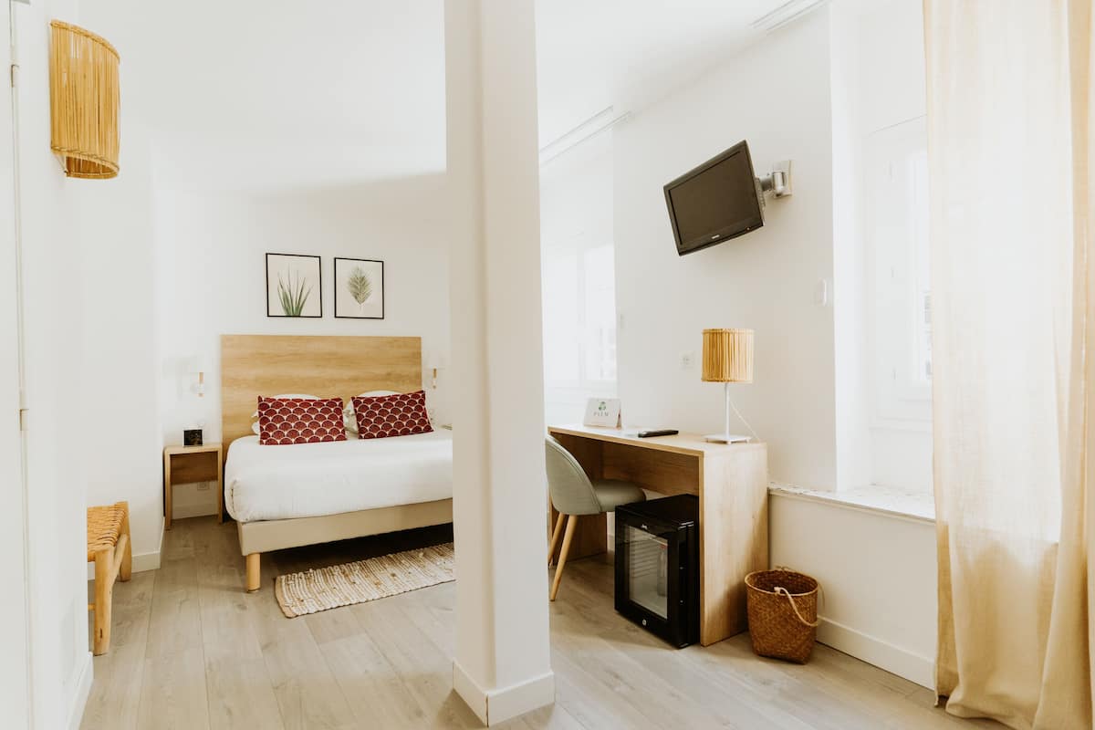 Une chambre moderne comprenant un lit, une table de chevet, une lampe, une télévision et un bureau avec une chaise.