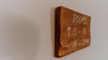 A wooden sign with room numbers and arrows indicating directions.