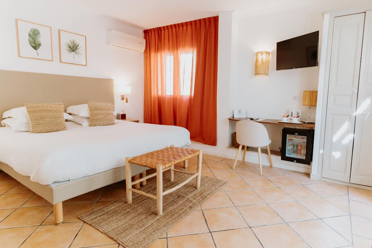 Une chambre d’hôtel équipée d’un lit, d’un bureau, d’une chaise, d’une télévision et d’un mini-bar.