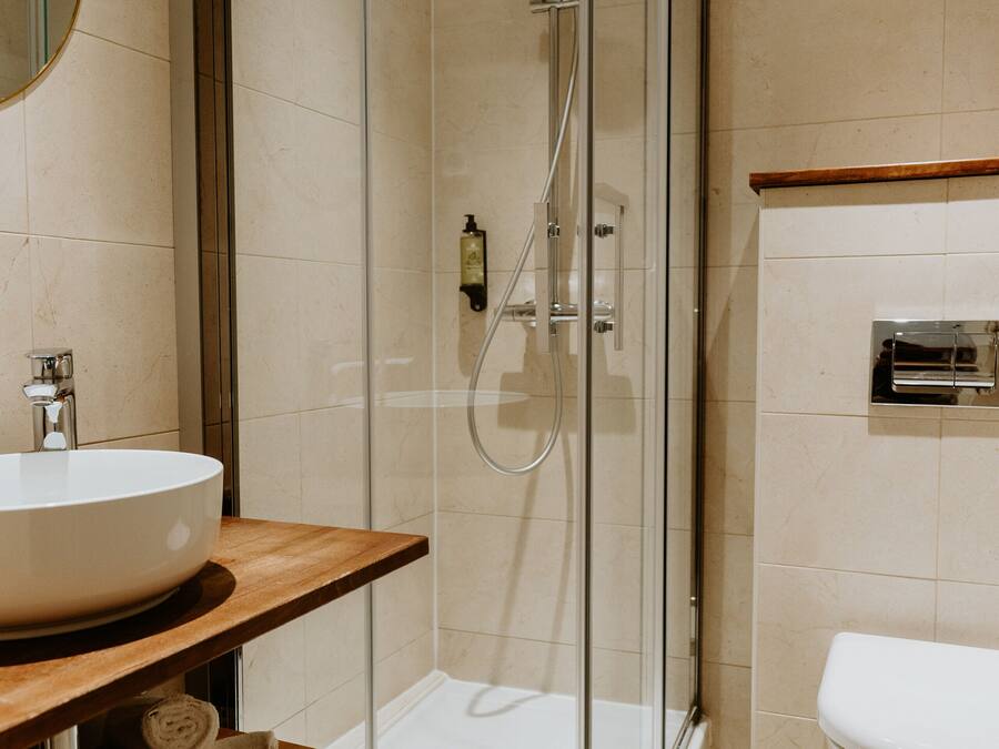 A modern bathroom with a glass-enclosed shower, a wooden vanity with a sink, and a toilet.