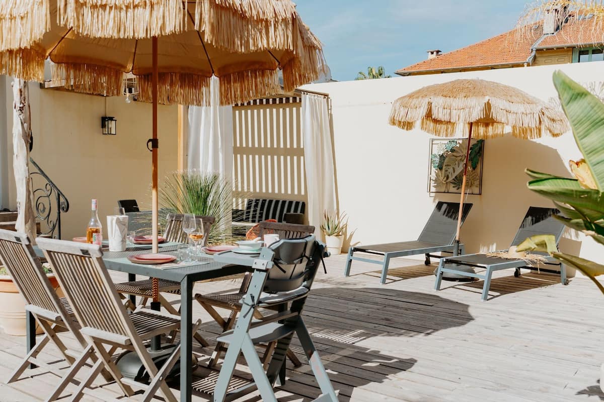 Un espace extérieur aménagé pour les repas, avec une terrasse en bois, des parasols en chaume et des chaises longues.