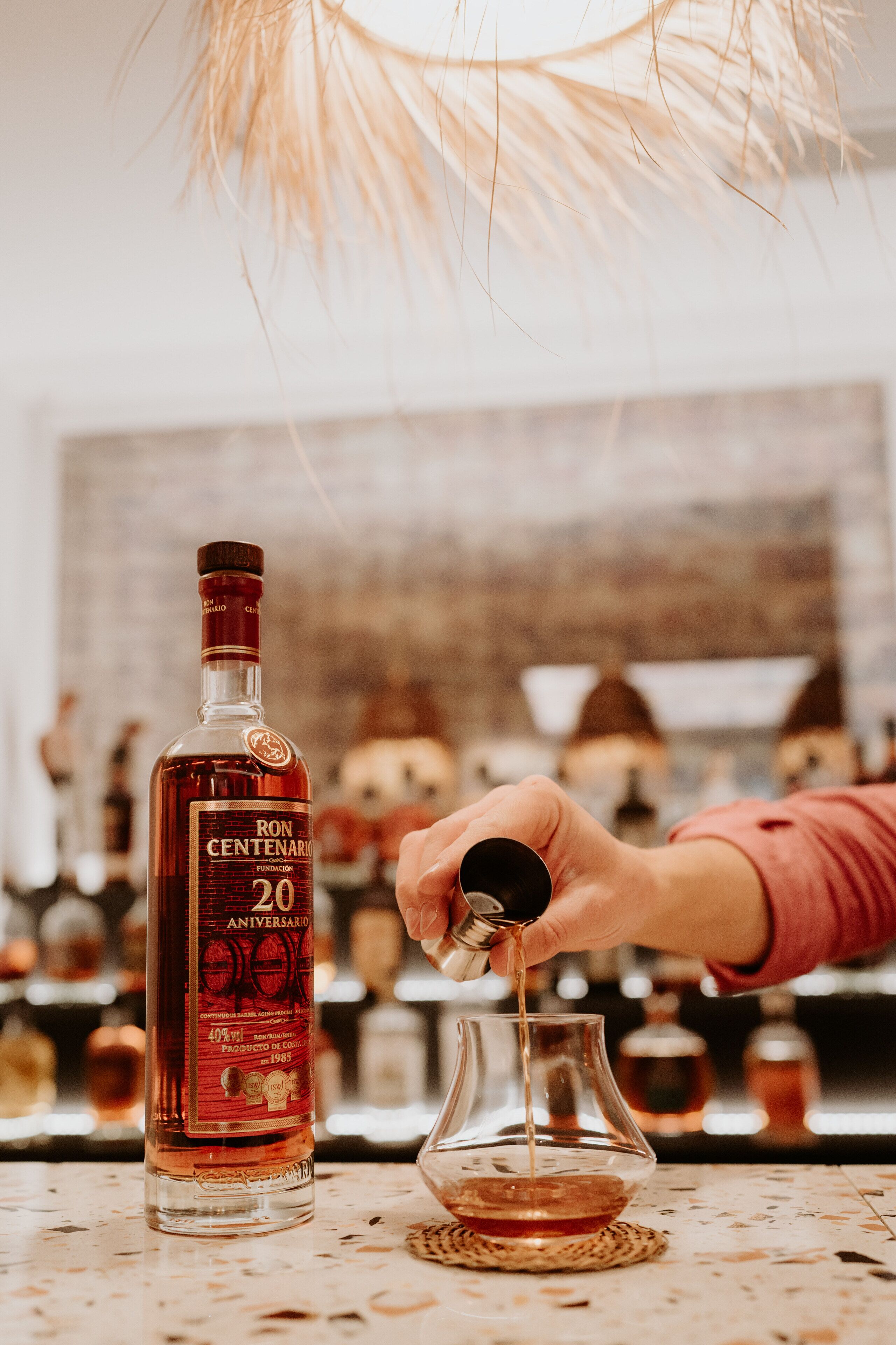 A bottle of Ron Centenario 20th Anniversary tequila being poured into a glass.