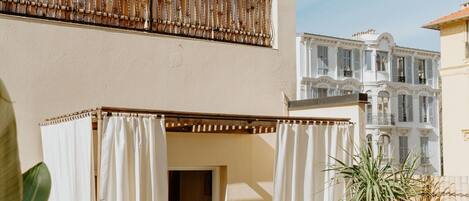 A balcony with a wooden railing, a white curtain, and a plant.