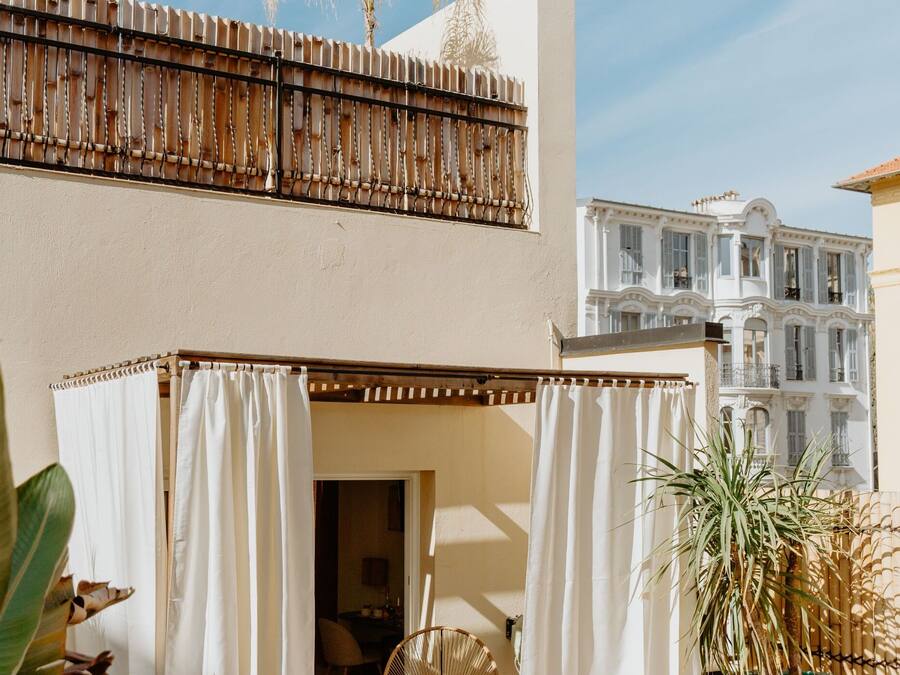 A balcony with a wooden railing, a white curtain, and a plant.