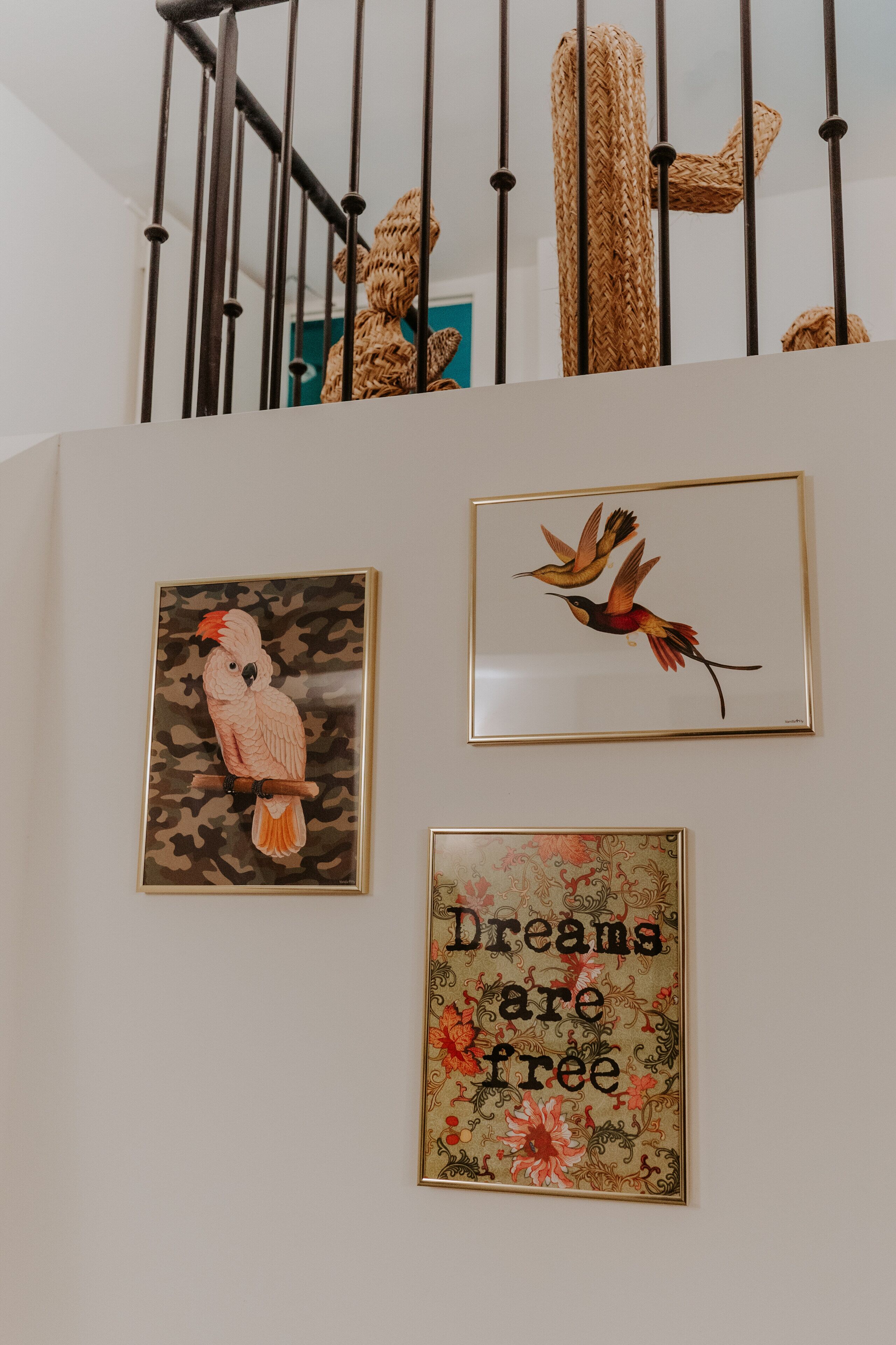 A staircase with a woven wall decoration, a framed bird painting, and a motivational quote on the wall.