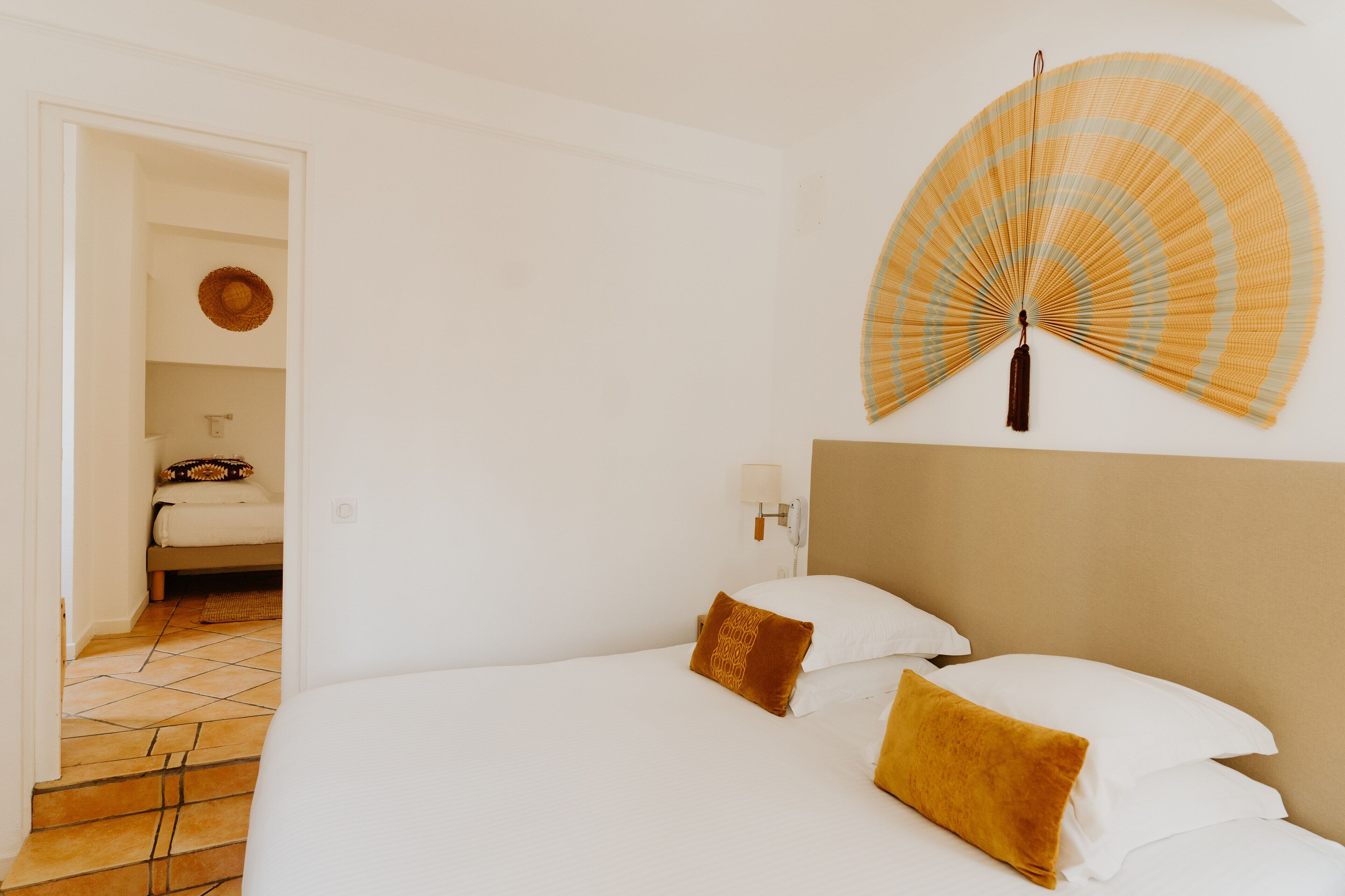 Une chambre d’hôtel avec un lit, un ventilateur mural et une porte donnant sur une salle de bain.