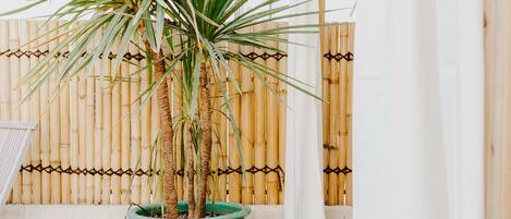 A balcony with a potted plant and a bamboo fence.