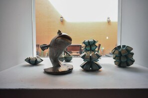 A sculpture of a horse on a pedestal, surrounded by geometric sculptures on a table by a window. - Hotel Casa Santo Tomas (Oaxaca)