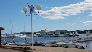 A marina with boats docked, a clear sky, and a street in the foreground.