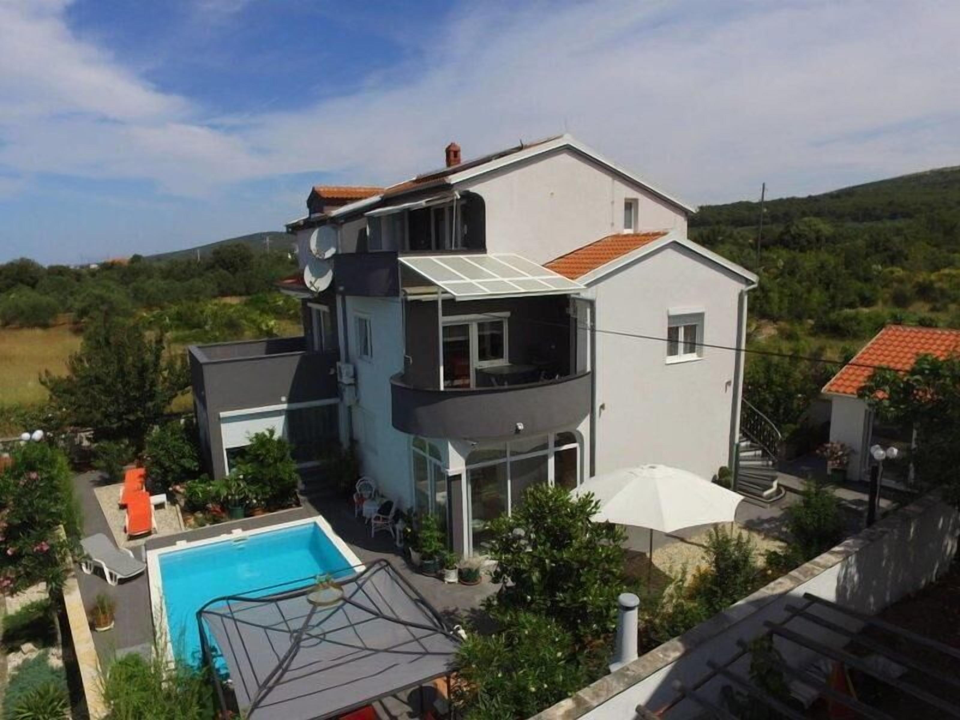 Ein zweigeschossiges Haus mit Schwimmbad, Balkon und Garten.