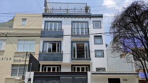 A multi-story residential building with a modern design, featuring balconies and large windows. - Comfortable apartment in Masaryk Avenue 1A (Polanco)