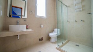 A modern bathroom with a glass-enclosed shower, a sink with a mirror, and a toilet. - Comfortable apartment in Masaryk Avenue 1A (Polanco)