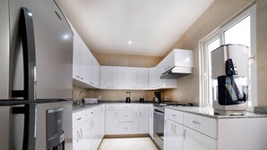 Een moderne keuken met witte kasten, een inbouwoven, een koffieapparaat en een waterdispenser.