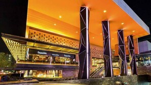 Een modern gebouw met een opvallende, oranje verlichte gevel, meerdere verdiepingen en een centrale trap.