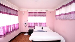 Un dormitorio con cama, mesita de noche, lámpara y cortinas.