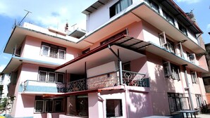 Un edificio de varios pisos con balcones, techo plano y chimenea visible.