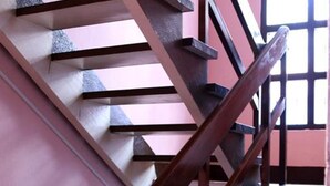 Una escalera de madera con barandilla y una ventana al fondo.
