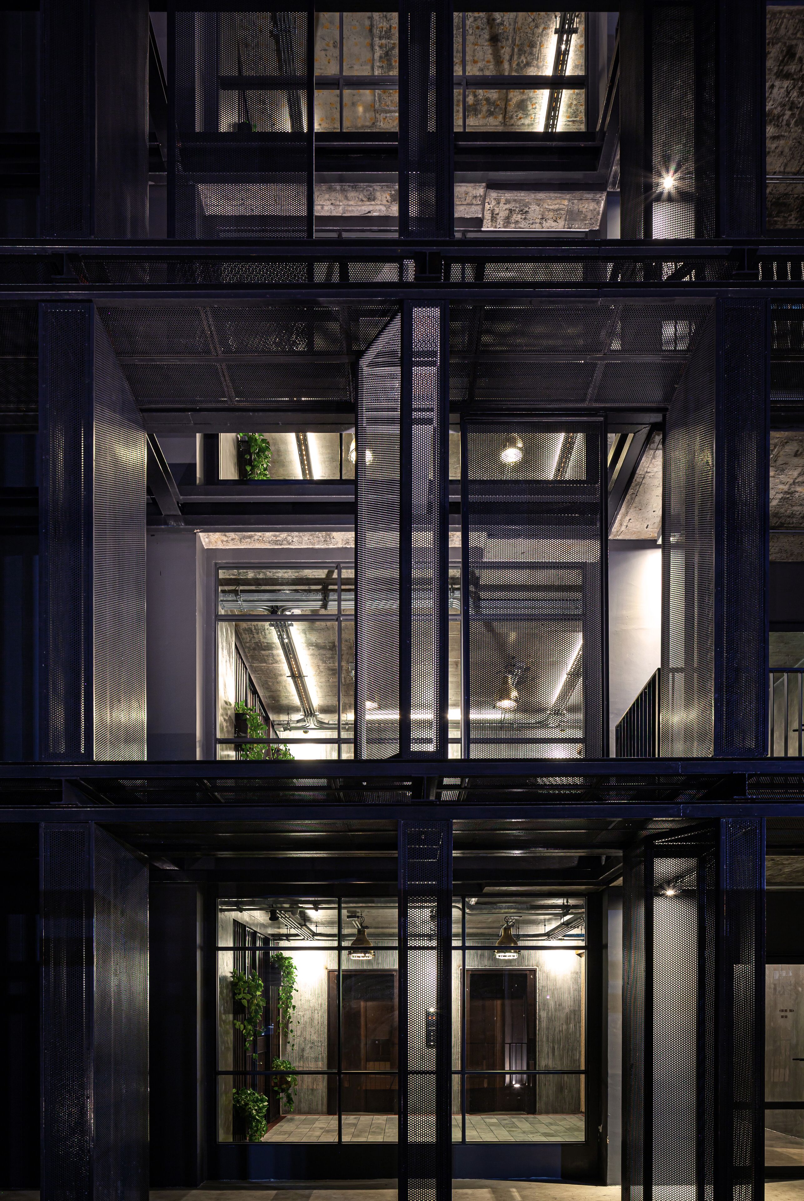 Ein mehrstöckiges Gebäude im modernen Industrie-Design, mit freiliegenden Decken, Metallgitterelementen und sichtbarer Konstruktion.