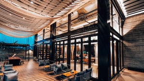 A modern interior with wooden flooring, black-framed glass doors, and a ceiling with a woven pattern. - Navakitel Design Hotel (Nakhon Si Thammarat)