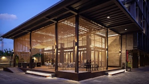 A modern building with a covered outdoor seating area and a large glass facade. - Navakitel Design Hotel (Nakhon Si Thammarat)