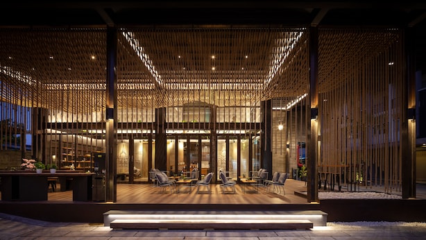 An outdoor seating area with tables and chairs, a wooden pergola structure, and a stone pathway. - Navakitel Design Hotel (Nakhon Si Thammarat)