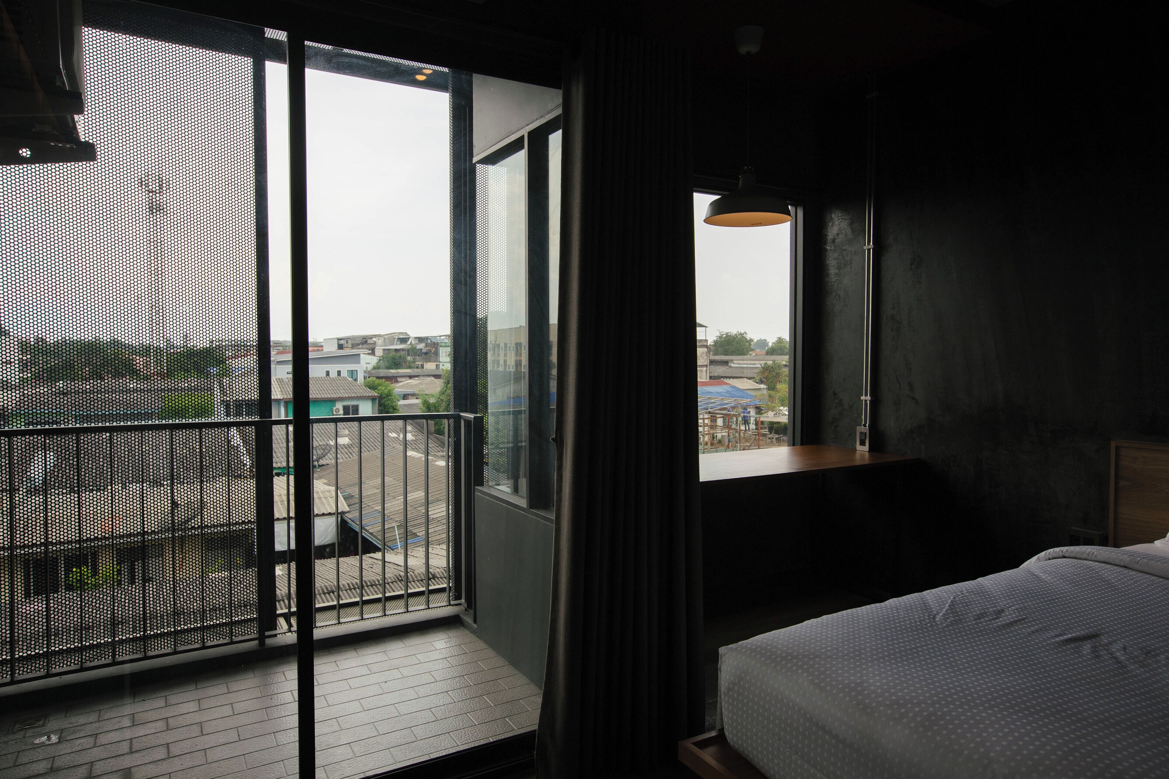 A hotel room with a large window, a balcony, and a bed.