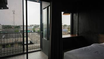 A hotel room with a large window, a balcony, and a bed.